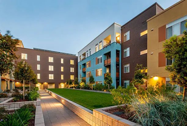 Modern multifamily apartment buildings around a landscaped courtyard at dusk
